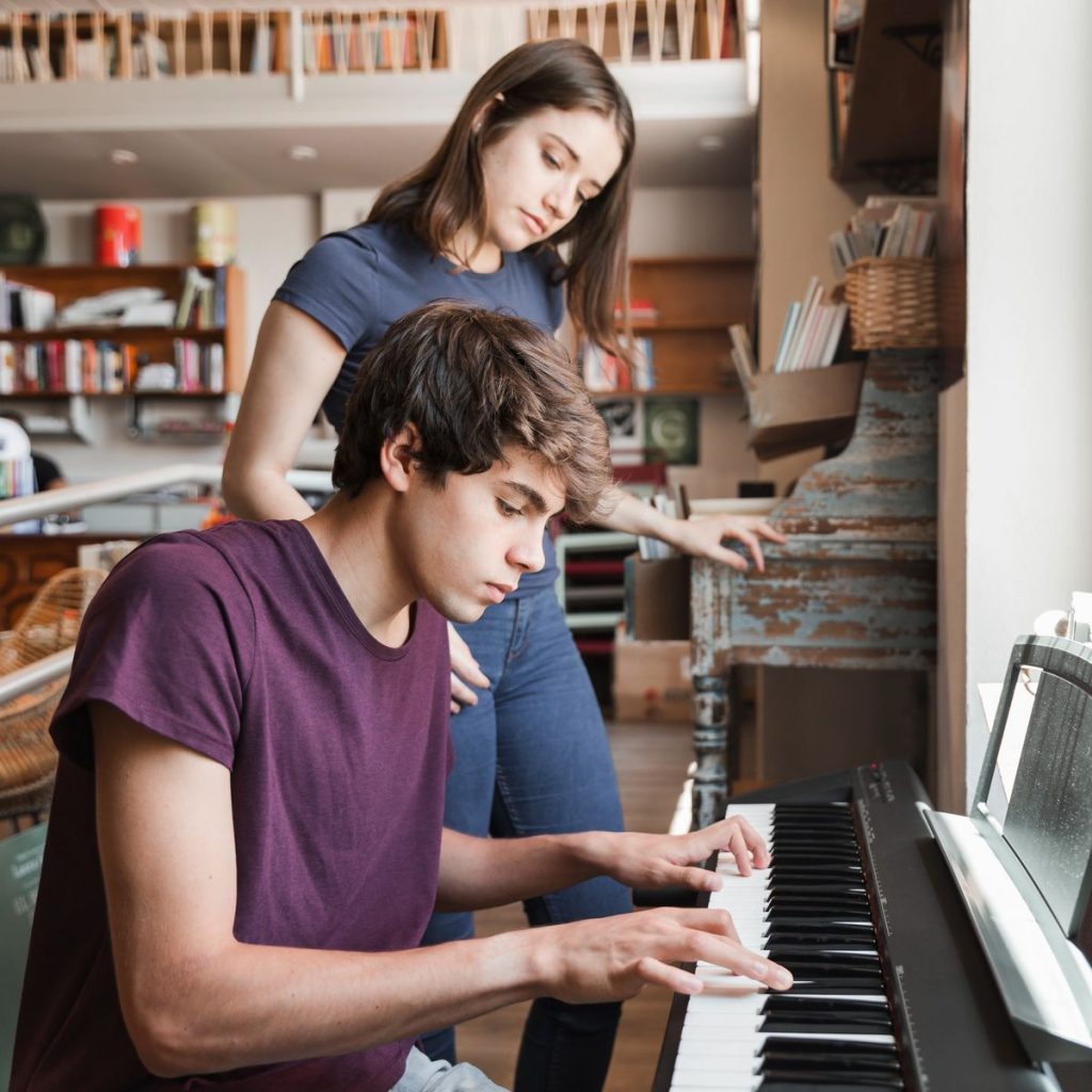 Adolescent jouant du piano sous la supervision d’une professeure en Belgique