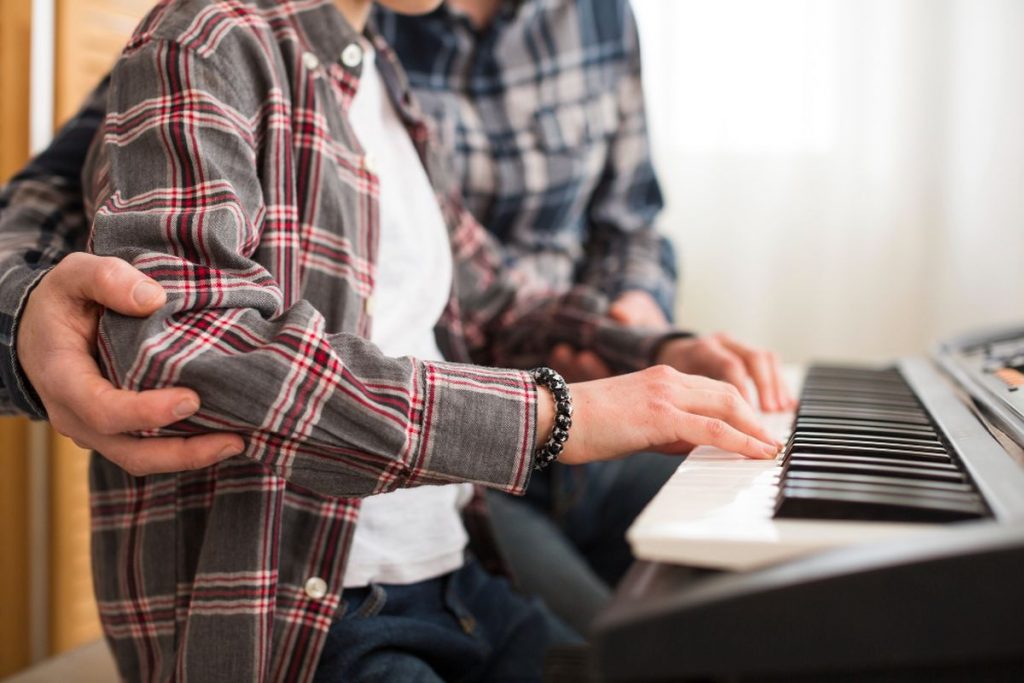 Professeur de piano guidant un élève pendant un cours particulier en Belgique
