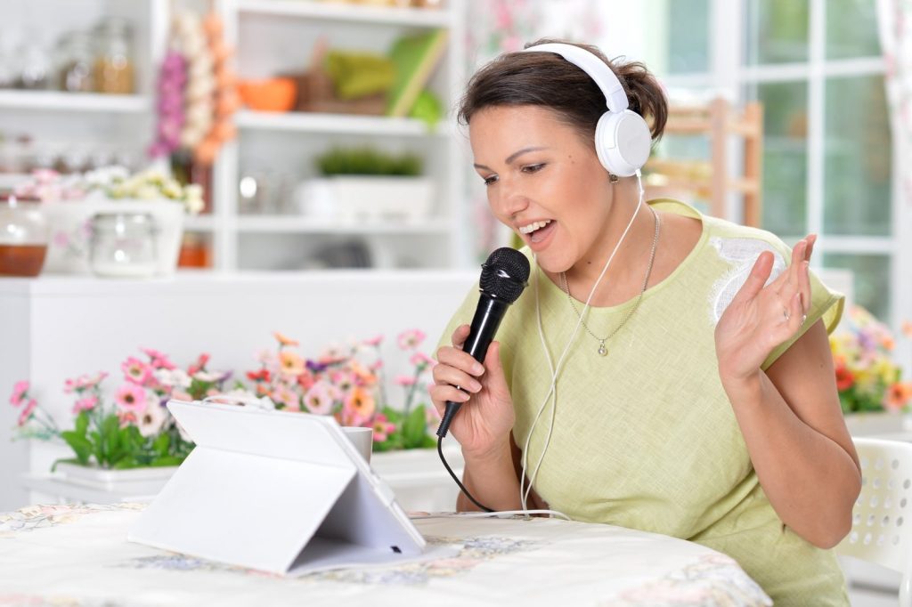 Cours de chant en ligne avec une élève chantant devant sa tablette avec casque et micro